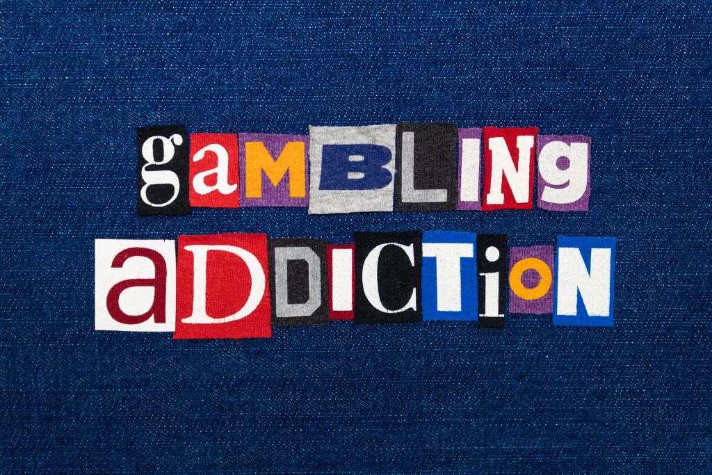 GAMBLING ADDICTION word text collage, multi colored fabric on blue denim, gambling urge addiction concept, horizontal aspect